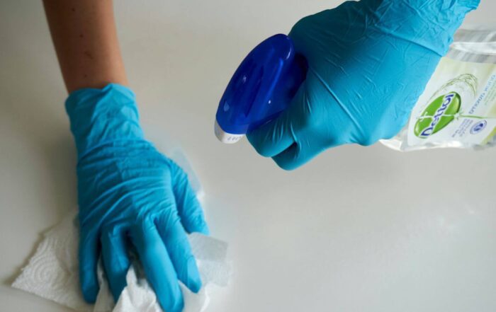 hands with gloves spraying bottle