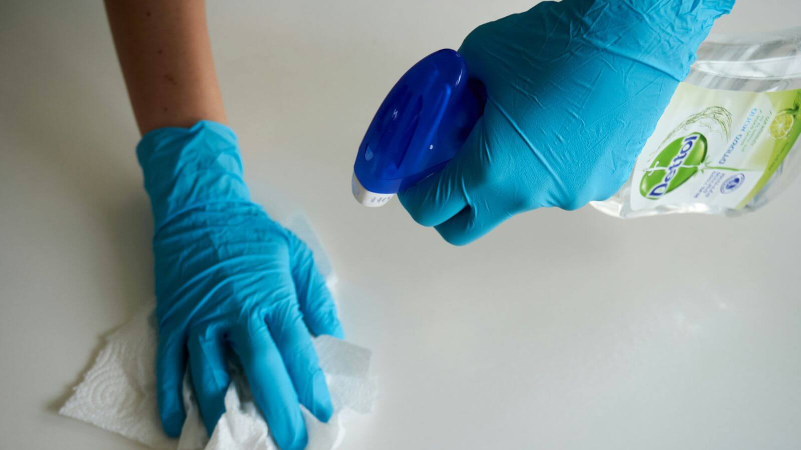 hands with gloves spraying bottle