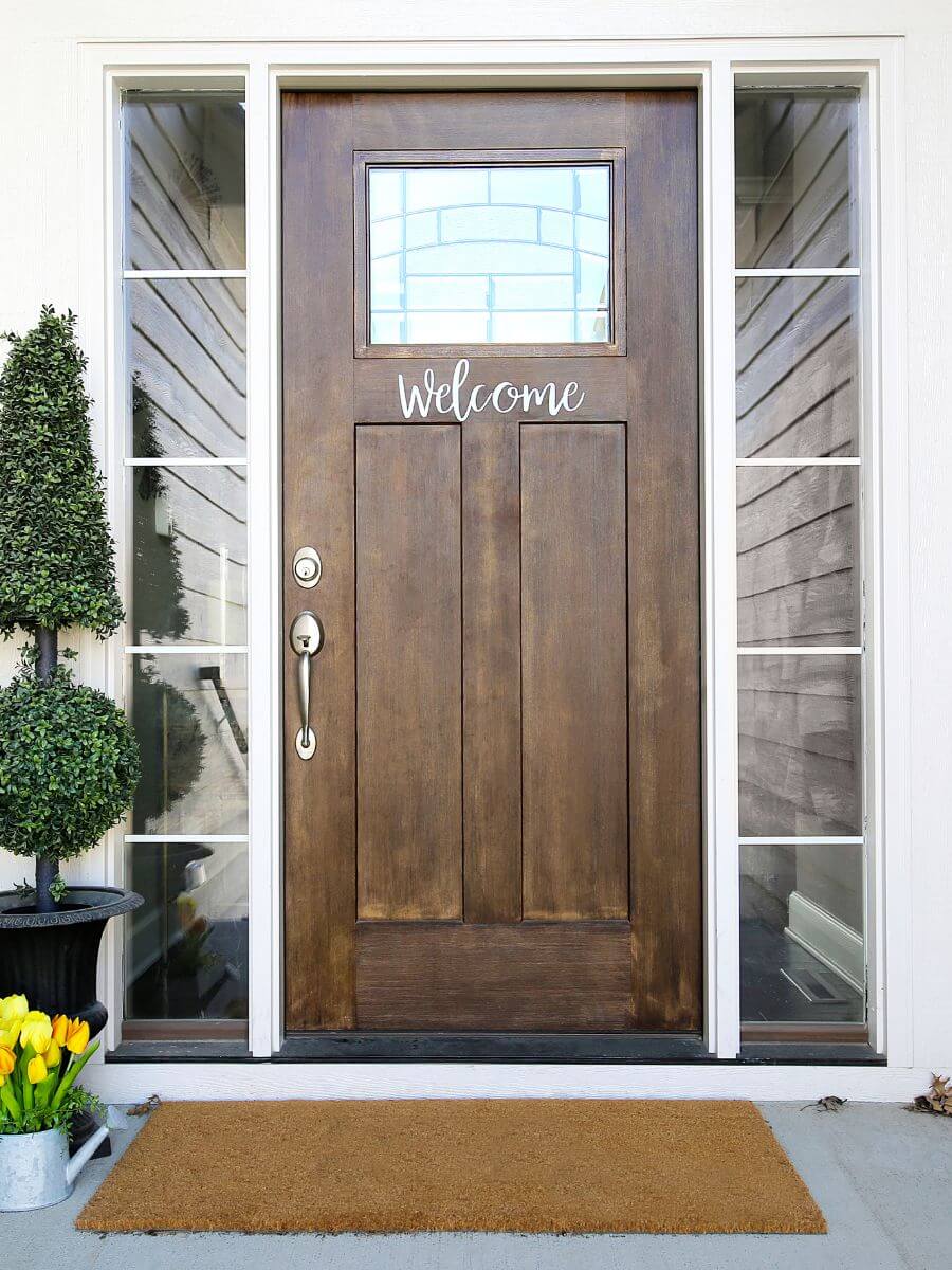 brown front door with a welcome sign and mat